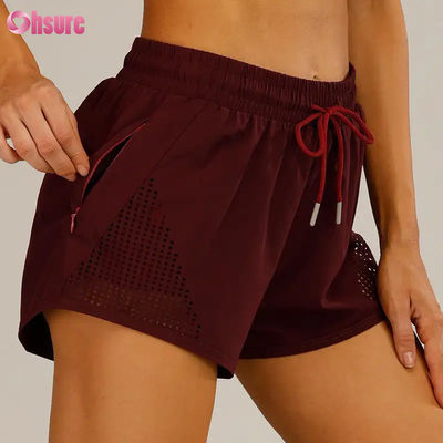 Großhandel Damen Sport Workout Shorts Atmungsaktive Laser Cut Jogging Shorts mit Warm-up Reißverschluss Seitentasche Einfarbig